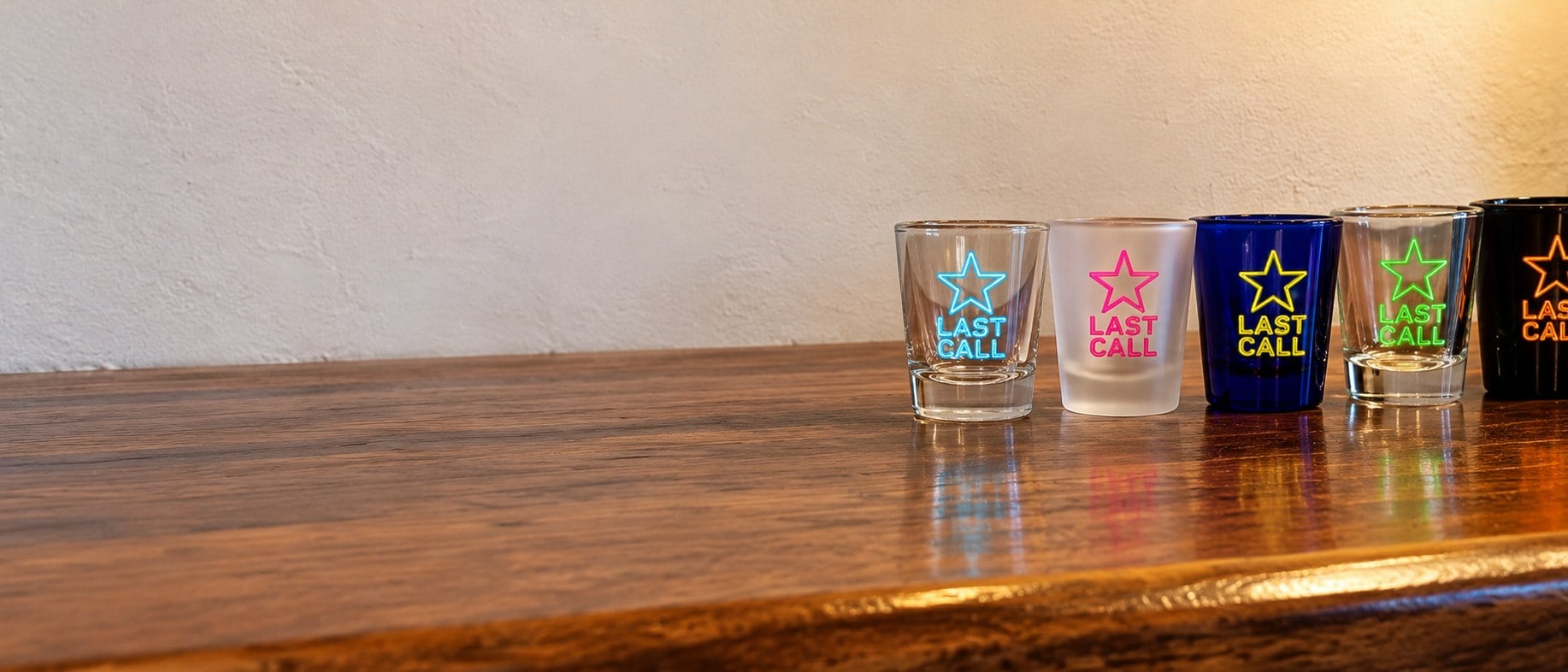 Custom printed shot glasses in bulk lined up on a bar top